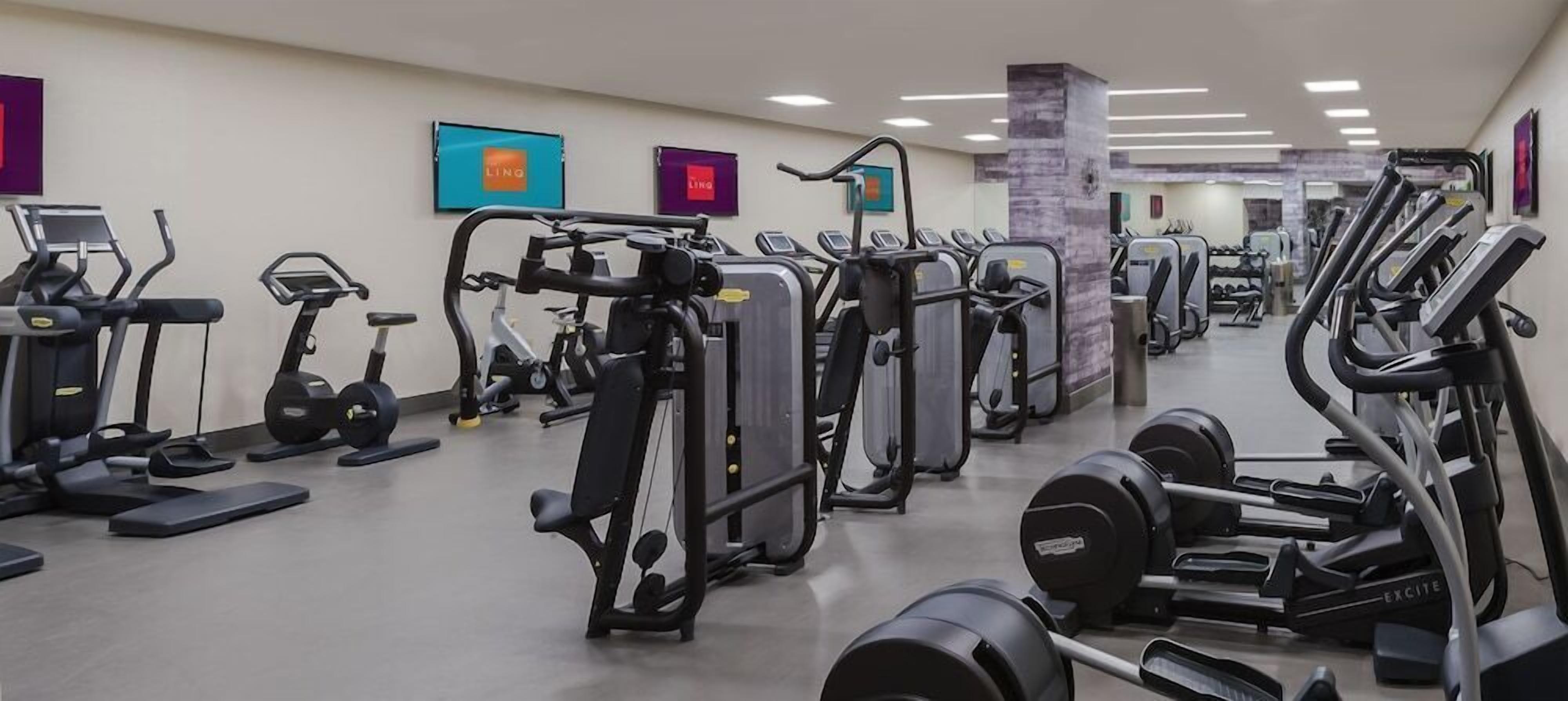 A gym with various exercise machines, including treadmills, elliptical trainers, and weight machines.