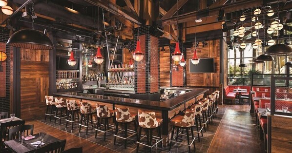 A bar area with a central island, bar stools, and a brick wall backdrop.