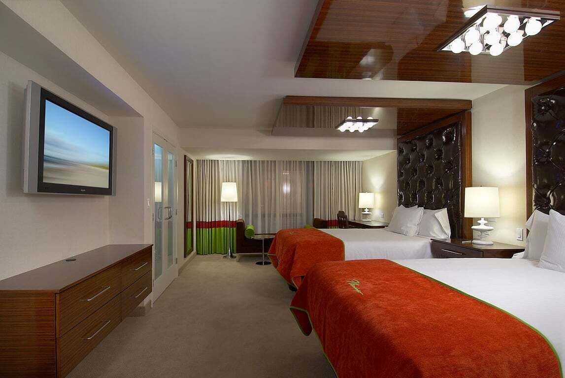 A hotel room with two beds, a TV, a desk, and a chair.