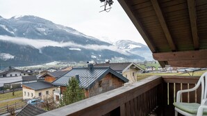 En træterrasse med udsigt over en landsby med huse og bjerge i baggrunden.
