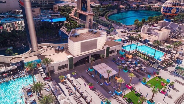 Vista aérea de un hotel con varias piscinas, una torre imponente y diversas zonas de estar al aire libre.