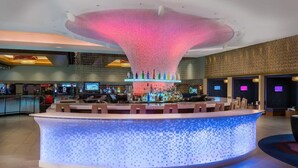 Eine moderne Bar mit einem einzigartigen Deckenstil und einer zentralen Bar.