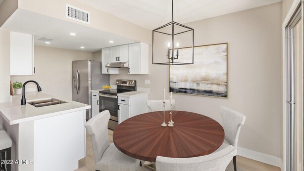 A modern kitchen with white cabinets, a stainless steel refrigerator, and a built-in oven. There is a dining area with a round wooden table and four chairs. - Newly Remodeled, Cozy & Private Condo - Beautiful Fountain Hills - Near Fountain (Fountain Hills)