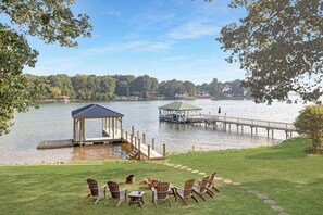 A lakeside view with a gazebo, dock, and outdoor seating area.