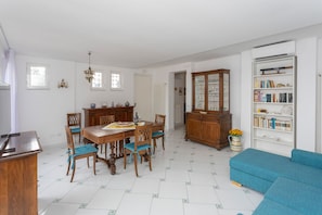 Un comedor con una mesa y sillas de madera, un aparador con puertas de cristal y una estantería.