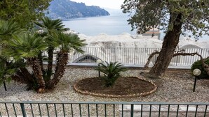 A coastal view with palm trees, a small garden, and a white fence. - Villa Lelle Amalfi (Amalfi)