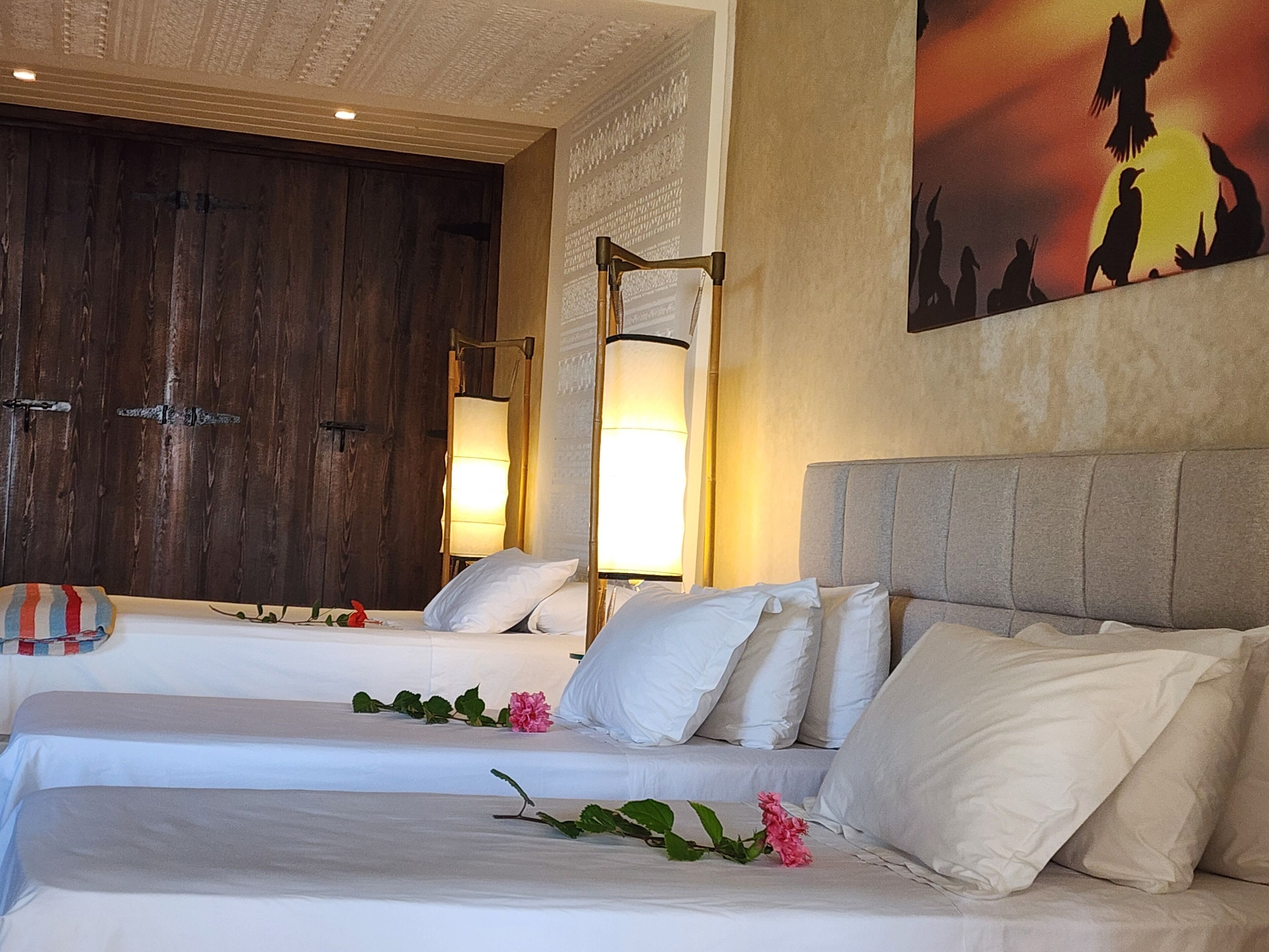 Ein Hotelzimmer mit zwei Betten, einer Holztür und einem Vogelgemälde an der Wand.