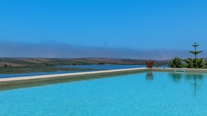 Un cielo azul despejado, una piscina y vistas a colinas distantes.