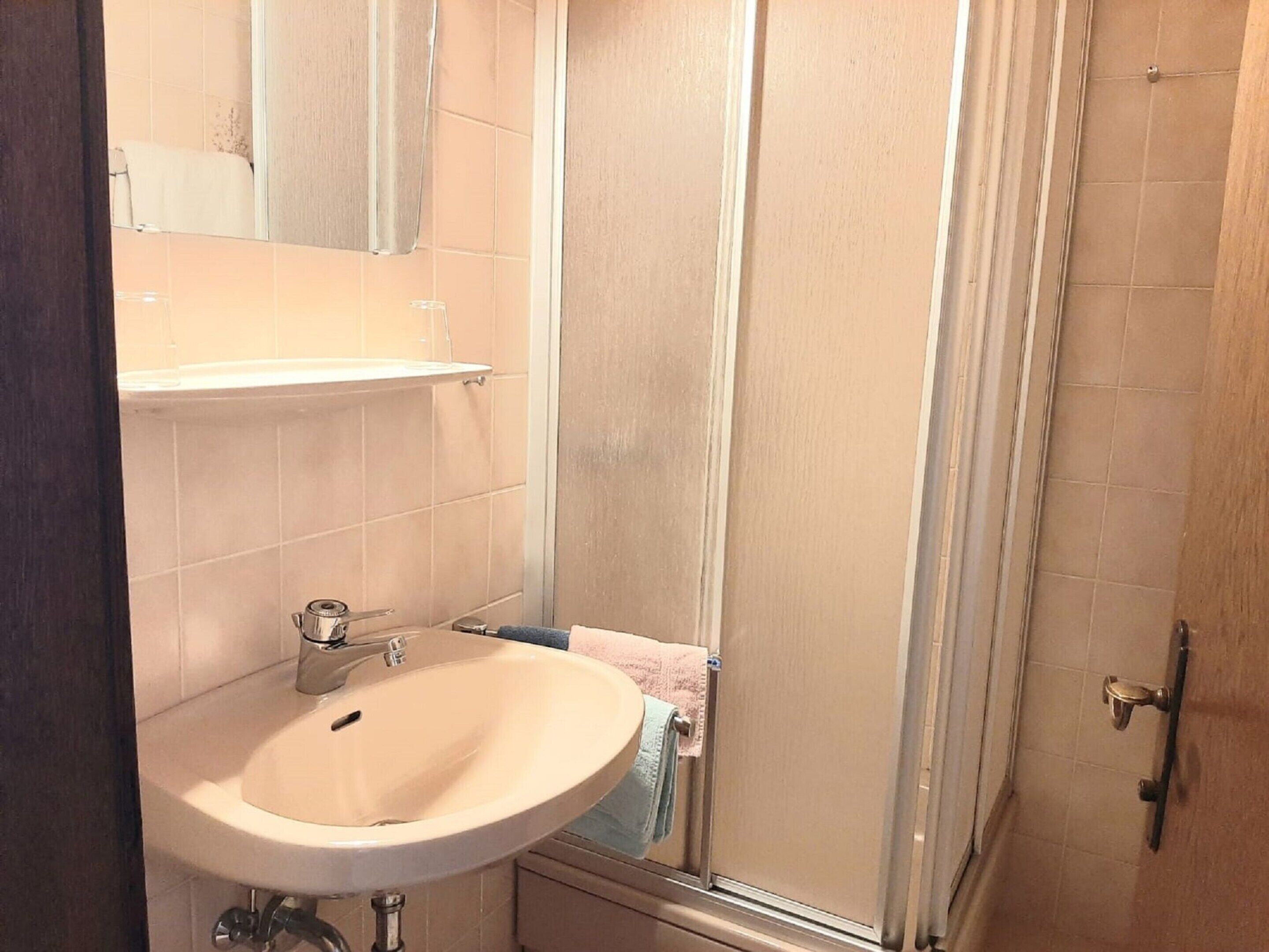Une salle de bain équipée d’un lavabo, d’un miroir et d’une cabine de douche.