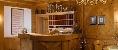 A wooden interior with a reception desk, a chandelier, and framed pictures on the wall.