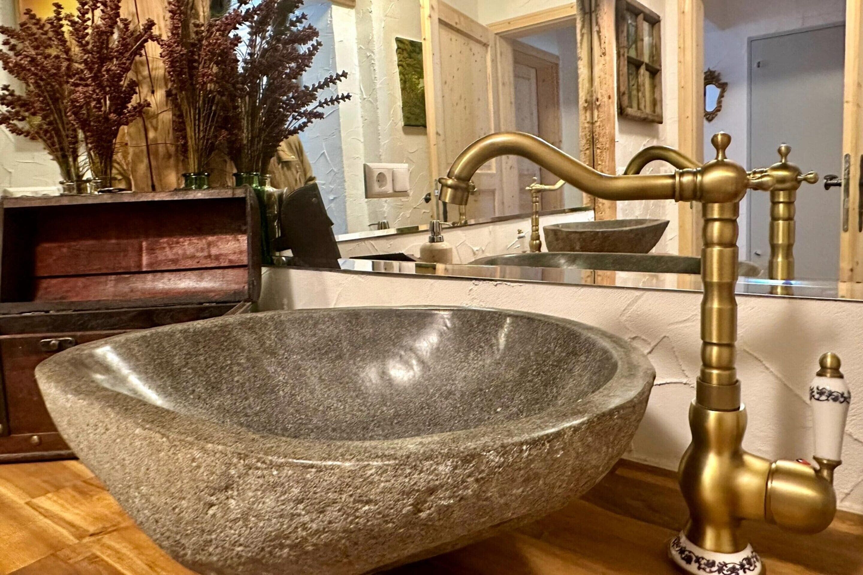 A stone sink with a brass faucet in a bathroom.