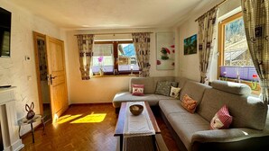 A cozy living room with a sofa, a coffee table, and a window with curtains.