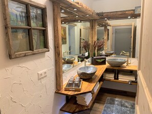 A bathroom with a rustic design, featuring a large mirror, wooden beams, and a stone basin sink. - Alpine Holiday Home in Lungau (Muhr)