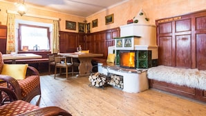 A cozy room with a fireplace, wooden furniture, and a dining area. - Farmhouse in St. Johann With Sauna (Sankt Johann im Pongau)