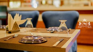 A dining table set with plates, cutlery, and a glass vase. - HOTEL A9 BARNALA (Barnala)