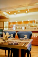 Una mesa de comedor dispuesta con platos, cubiertos y un florero de vidrio.