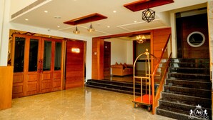 A hotel lobby with wooden doors, a chandelier, a lift, and a staircase. - HOTEL A9 BARNALA (Barnala)
