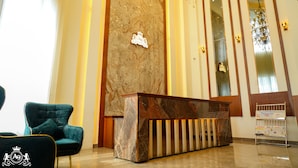 A reception area with a marble wall, a reception desk, a chandelier, and a blue armchair. - HOTEL A9 BARNALA (Barnala)