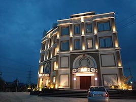 Un edificio de varios pisos con una entrada destacada y señalización iluminada.
