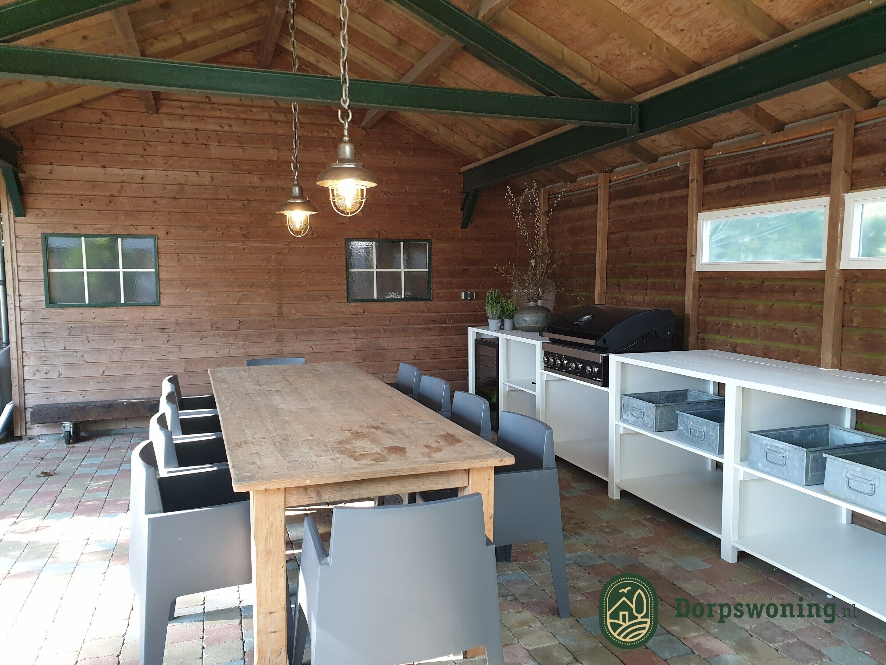 Una cabaña rústica de madera con una mesa de comedor, sillas, una parrilla y estanterías.