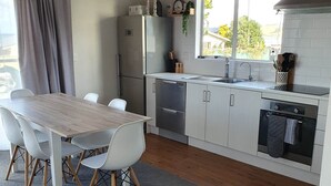 Une cuisine moderne avec des meubles blancs, un réfrigérateur en acier inoxydable et une fenêtre offrant une belle vue.