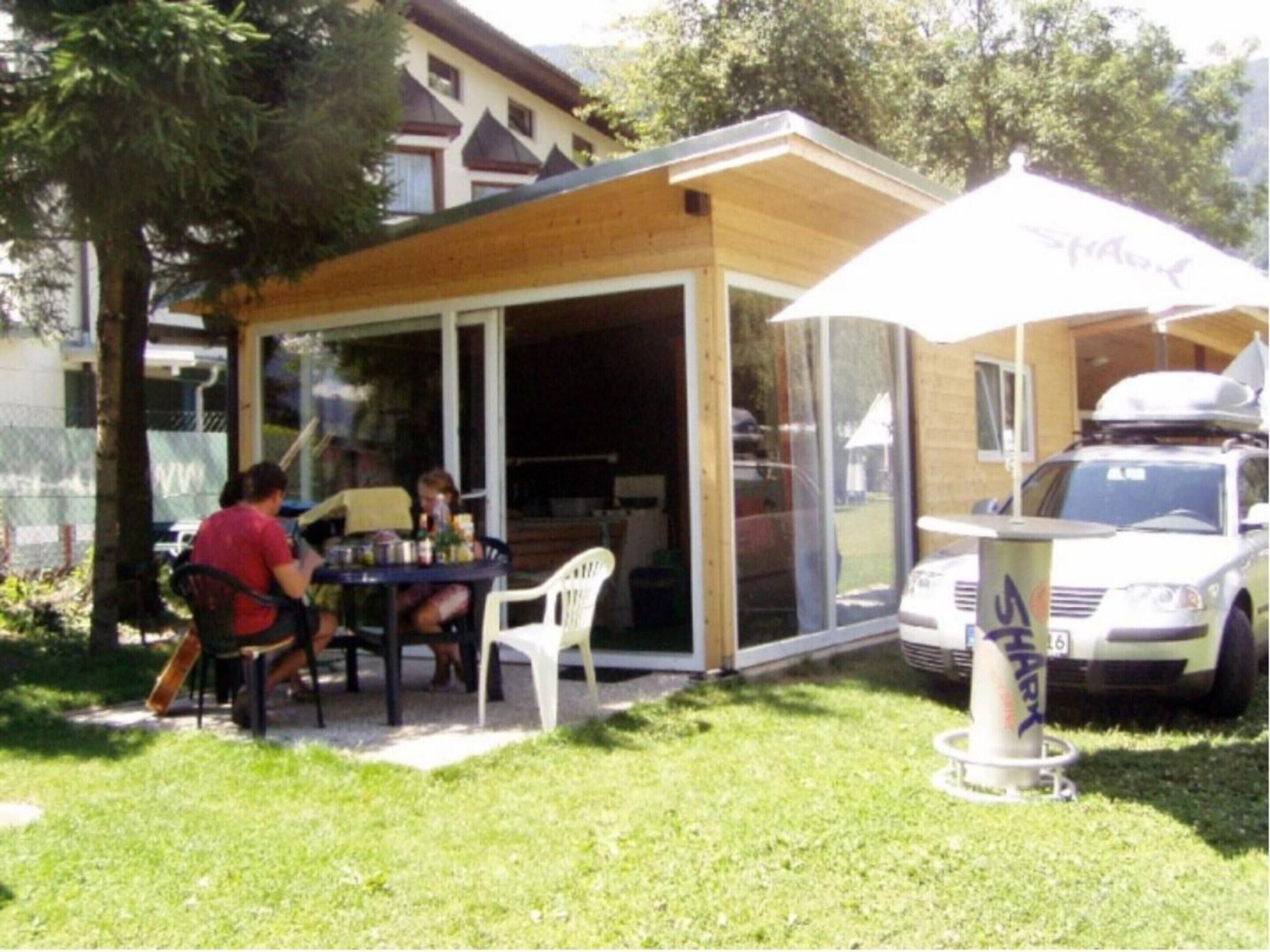 An outdoor patio with a table and chairs, a covered seating area, and a car parked nearby.