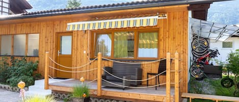 A wooden cabin with a porch, a bicycle rack, and a mountain view.