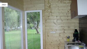 A small kitchen with wooden walls, a sink, and a window overlooking a grassy area. - Bungalow by Lake Ossiach With Mountain Views (Steindorf am Ossiacher See)