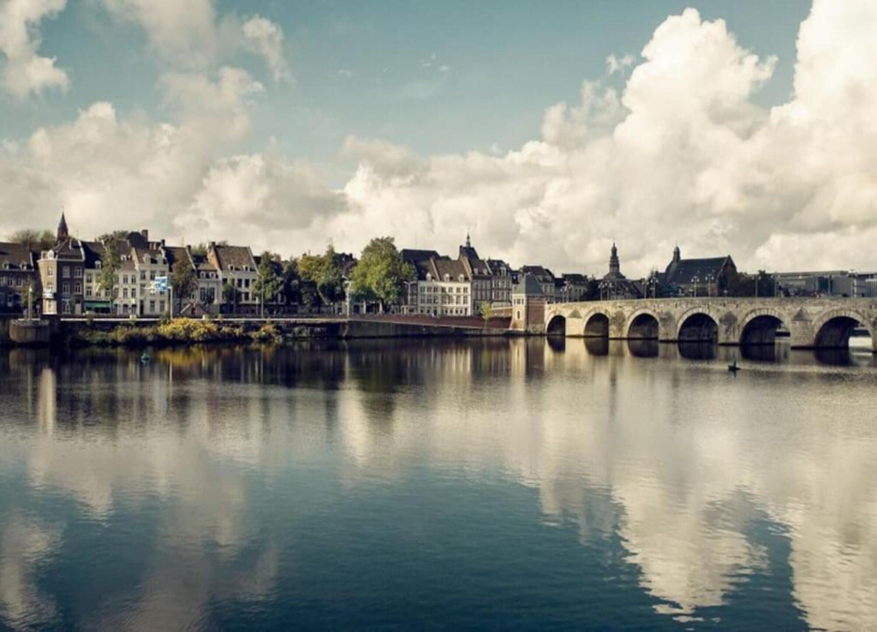 Een rivier met een stenen brug en gebouwen langs de oever.