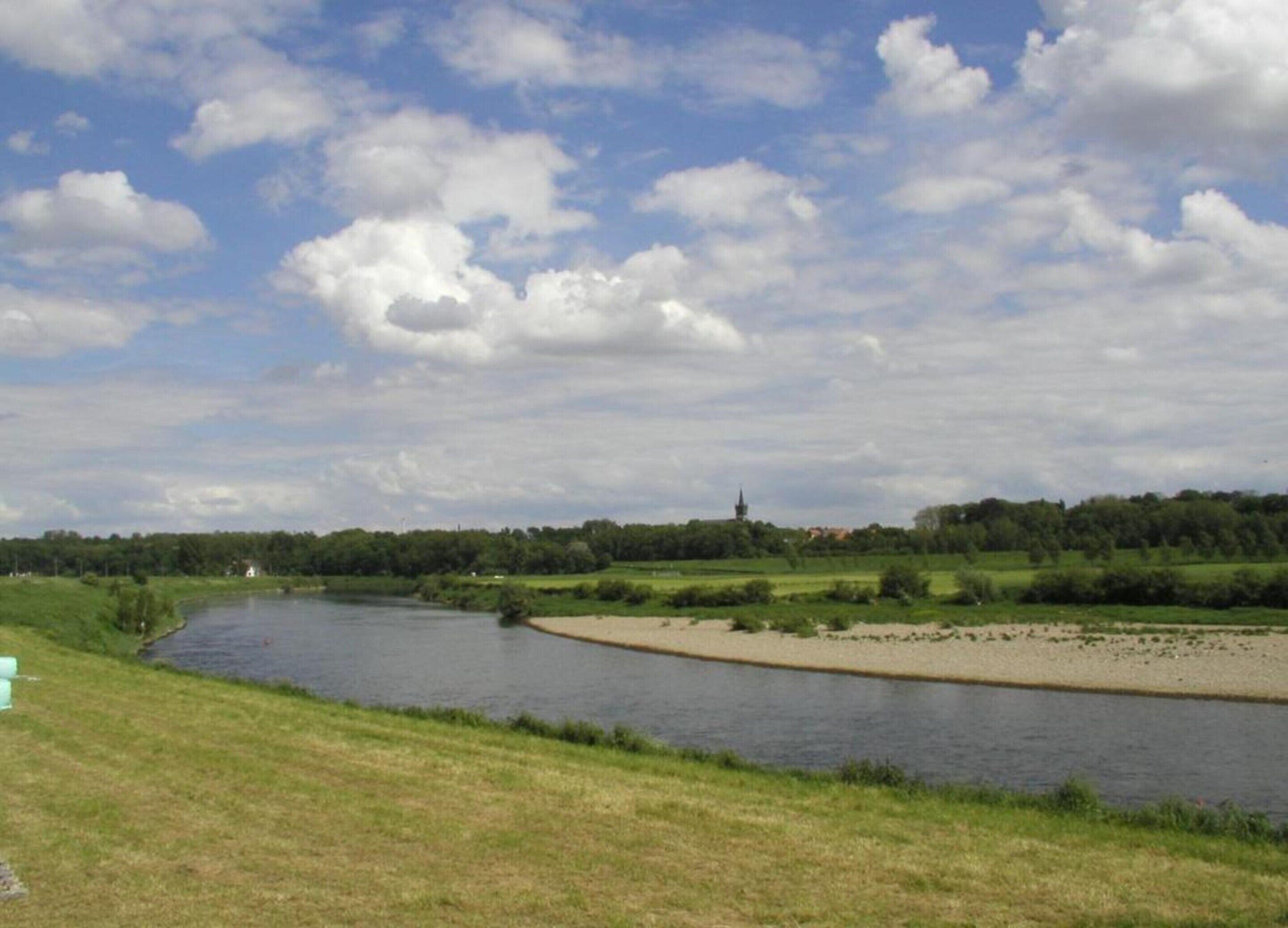 A river with a grassy bank and a distant church.