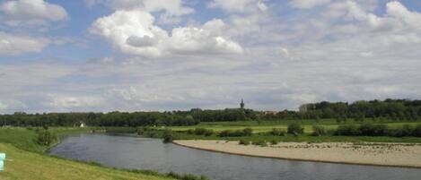 A river with a grassy bank and a distant church.