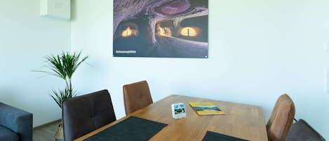 Una sala de conferencias con una mesa de madera, cuatro sillas, una planta en maceta y un cuadro con una imagen de una cueva.