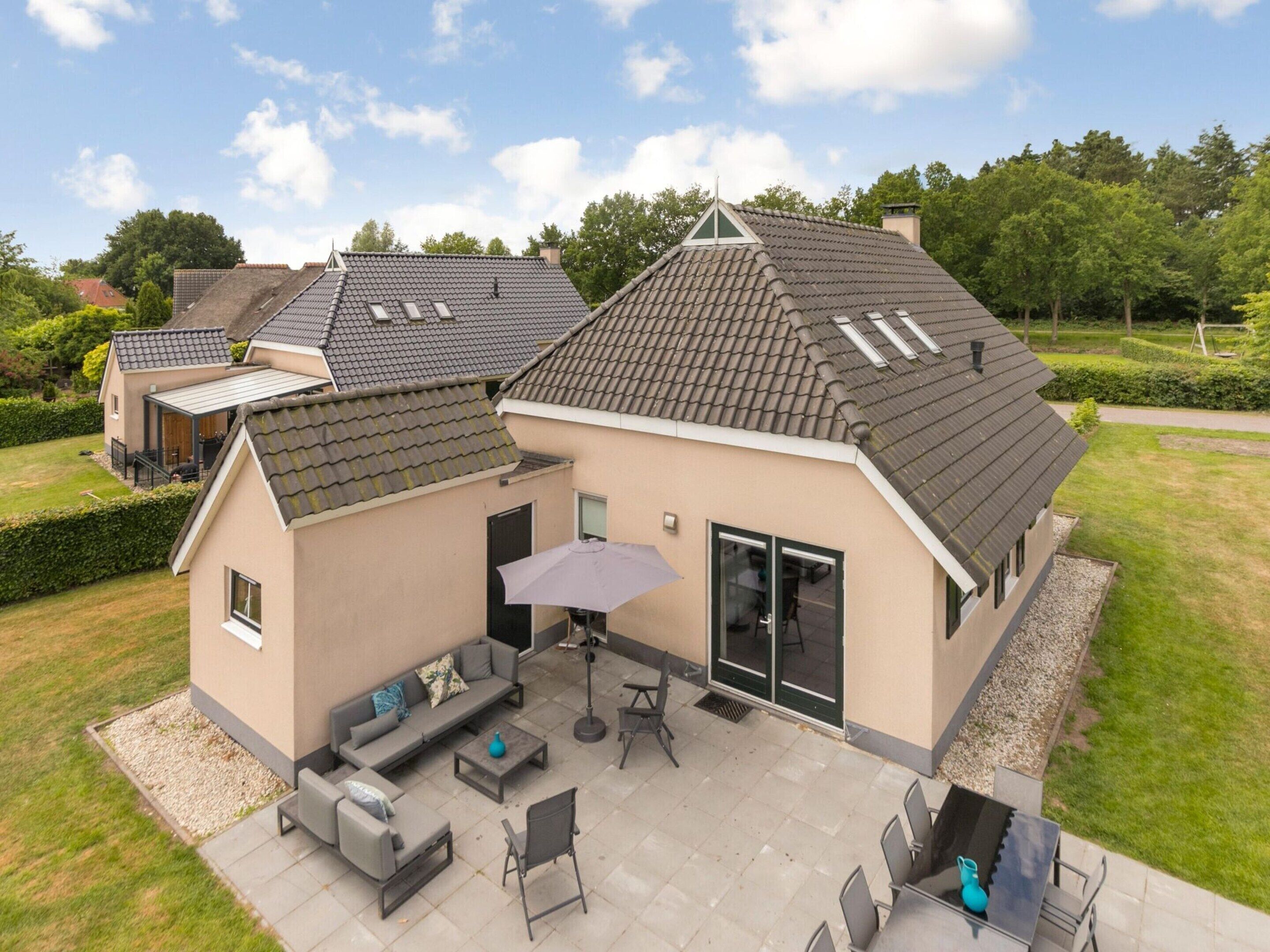 A modern house with a patio area featuring outdoor furniture and a barbecue.