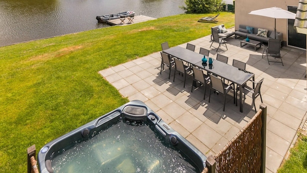 Een terras met een jacuzzi, buitenzitplaatsen en uitzicht op een rivier.