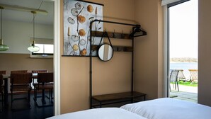 Een hotelkamer met een bed, een eethoek met stoelen en een tafel, een groot raam met uitzicht op de omgeving, en een spiegel aan de muur.