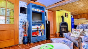 Una sala de estar acogedora con techo de madera, una estantería azul, chimenea y un sofá estampado.