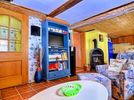 Una sala de estar acogedora con techo de madera, una estantería azul, chimenea y un sofá estampado.