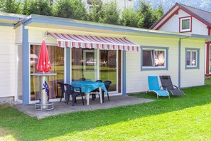 A small house with a covered patio, a table with chairs, and two lounge chairs. - Bungalow in Bodensdorf Near Gerlitzen Ski Area (Steindorf am Ossiacher See)
