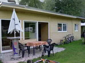 A house with a patio, a table, and chairs. There is a bicycle parked outside. - Bungalow in Bodensdorf Near Gerlitzen Ski Area (Steindorf am Ossiacher See)