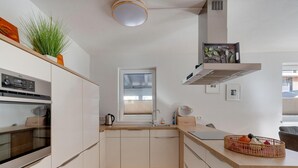 A modern kitchen with white cabinets, a wooden countertop, a built-in oven, a window, and a ceiling light. - Holiday Home in Niedernsill Near ski Area (Niedernsill)