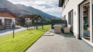A modern house with a patio, a fenced yard, and mountain views. - Holiday Home in Niedernsill Near ski Area (Niedernsill)
