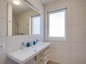 Une salle de bain moderne avec un lavabo blanc, un miroir et une fenêtre.