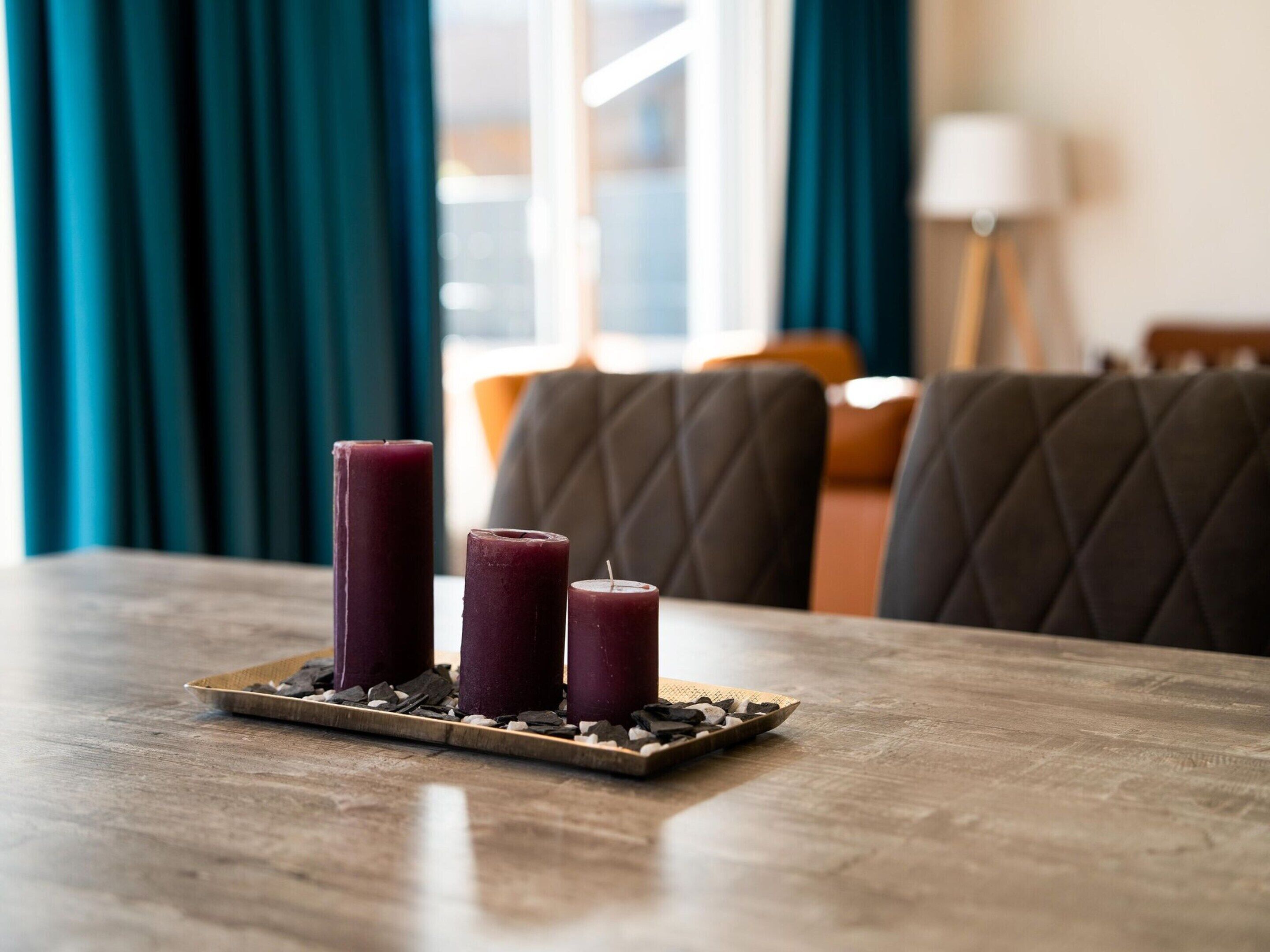 Een eettafel met drie kaarsen op een stenen dienblad.