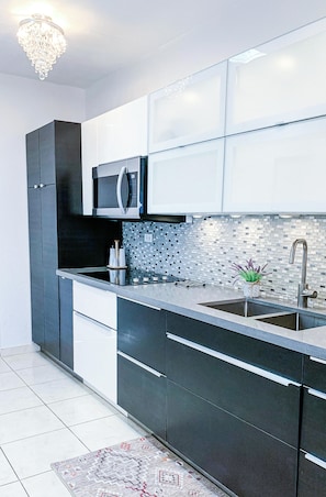 A modern kitchen with dark cabinetry, a stainless steel sink, and a microwave.