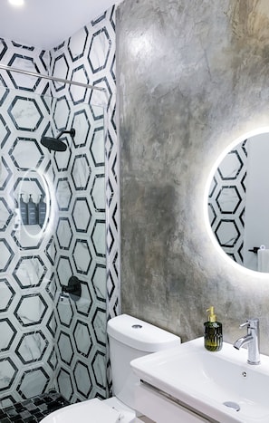 A bathroom with a white toilet, a sink with a gold soap dispenser, and a shower with a black and white hexagonal tile pattern. - Modern Chic House closed to the airport and beach (Carolina)