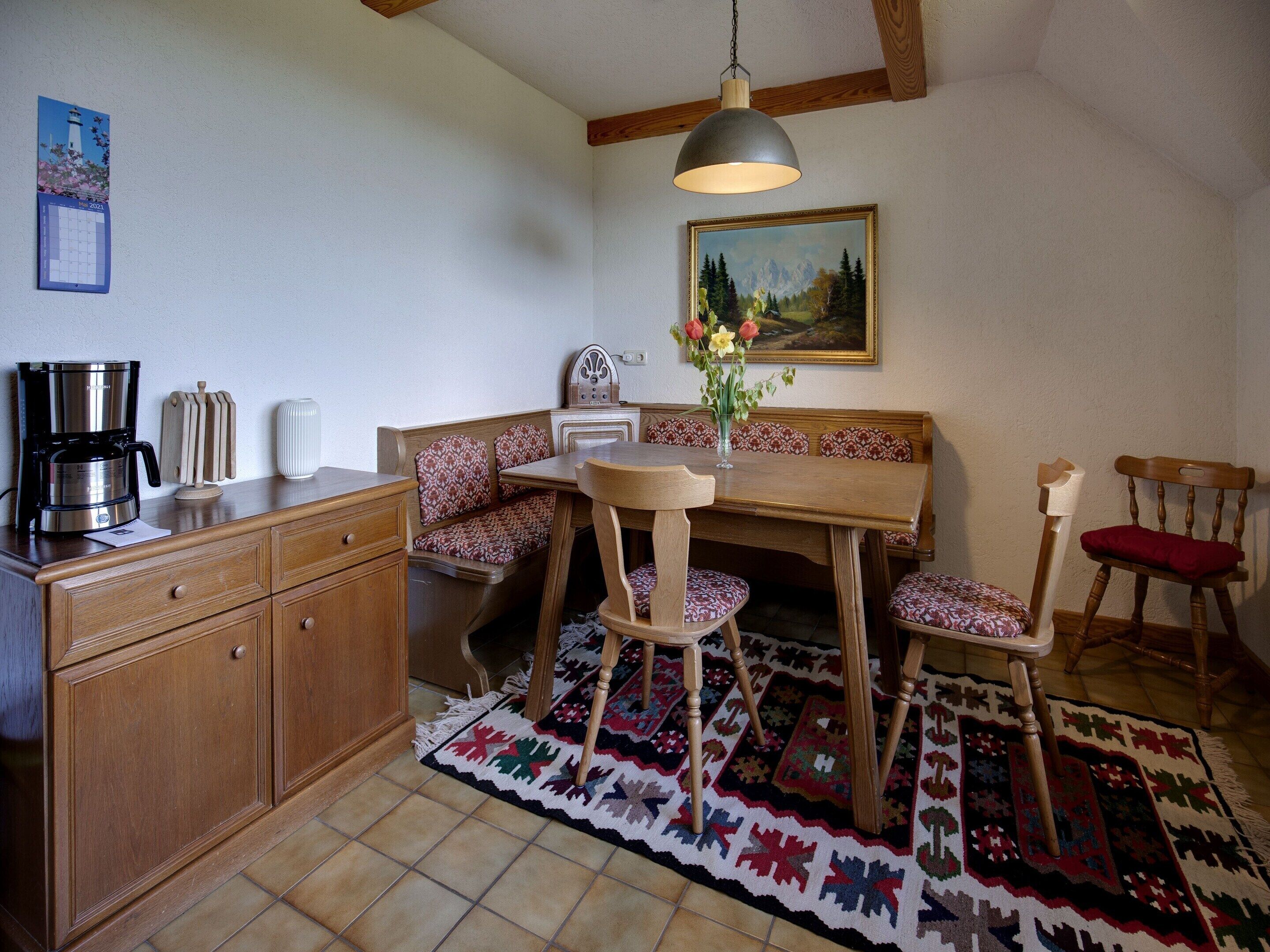 A cozy dining area with a wooden table, bench seating, and a coffee maker.
