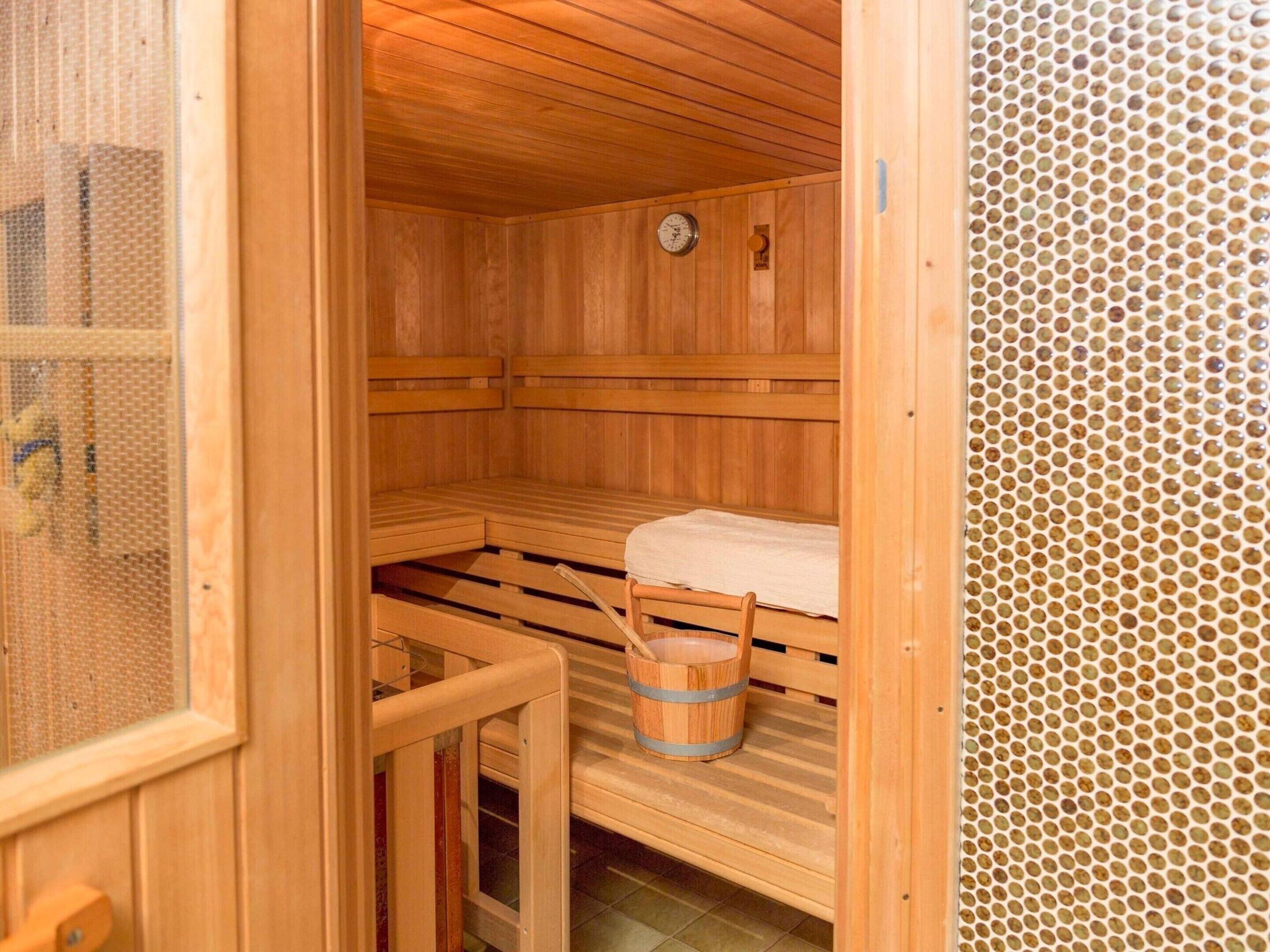 Eine Holzsauna mit Bänken, einem Holzfass und einem sichtbaren Temperaturanzeiger.