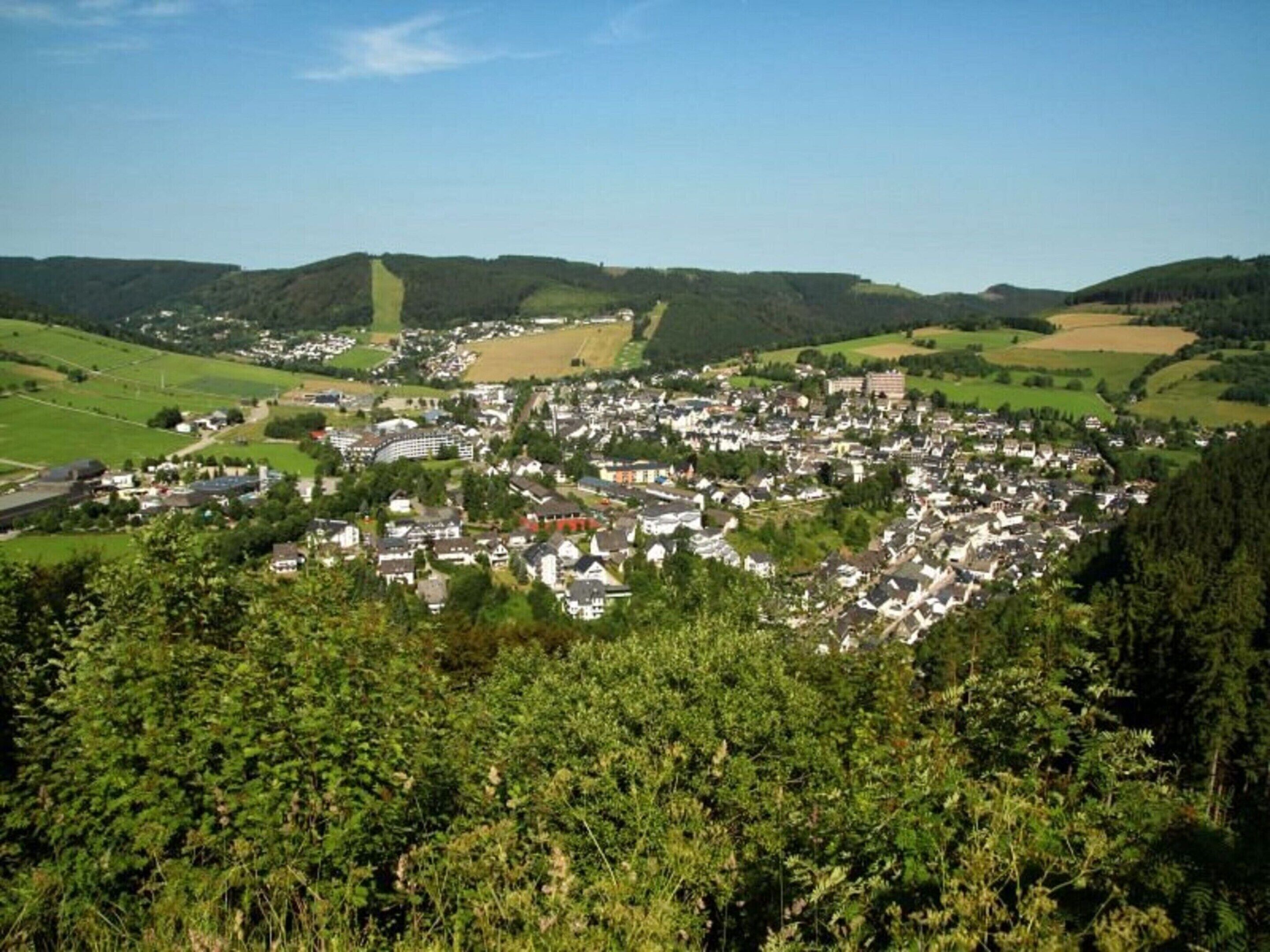 A town with a central square, surrounded by residential buildings and green fields.