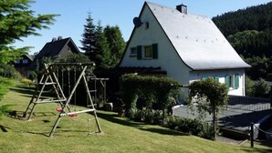 Una casa amb un teulat inclinat, un tobogan i un jardí ben cuidat.