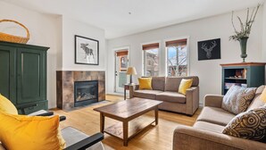 Una sala de estar con chimenea, dos sofás, una mesa de centro y una estantería.